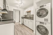 Thumbnail 11 of 42 - a kitchen with white cabinetry and a washer and dryer