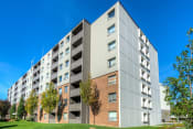 Thumbnail 1 of 16 - a large apartment building with trees in the foreground and a blue sky in the background