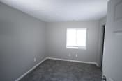 Thumbnail 8 of 11 - Empty bedroom with a window and a door at Canterbury House apartments in Logansport, Indiana