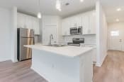 Thumbnail 22 of 40 - a white kitchen with a large island and a stainless steel refrigerator