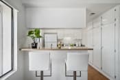 Thumbnail 61 of 100 - a kitchen with white cabinets and a counter with two white chairs