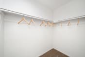 Thumbnail 45 of 100 - a walk in closet with white walls and wooden clothes hangers