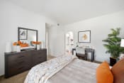 Thumbnail 8 of 100 - a bedroom with white walls and a large bed with orange pillows