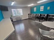 Thumbnail 7 of 11 - a laundry room with a row of washing machines and a table and chairs
