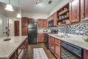 Thumbnail 8 of 18 - Kitchen with Wood Cabinets & Granite Countertops at Overlook at Stone Oak Park Apartments, San Antonio, Texas