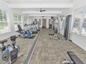 Thumbnail 51 of 61 - Fitness room surrounded by windows with cardio and weight machines, ceiling fans, and carpet flooring