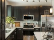 Thumbnail 5 of 78 - Luxury designer kitchen with dark wooden cabinets & stainless appliances in Charlotte, NC apartments