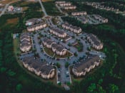 Thumbnail 15 of 61 - Aerial drone view of Riverstone Apartments with outdoor parking surrounded by lush green space