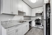 Thumbnail 9 of 42 - a kitchen with white cabinets and granite counter tops
