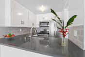 Thumbnail 3 of 21 - a kitchen with white cabinets and a vase with a plant