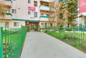 Thumbnail 17 of 17 - an apartment building with a green fence and a grey walkway leading to the front door