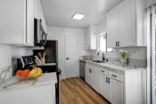 Thumbnail 1 of 19 - a kitchen with white cabinets and a bowl of fruit on the counter