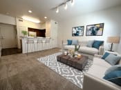 Thumbnail 9 of 15 - Liberty Landing Apartments Heathrow Floor Plan Living Room with couches, barstools and coffee table. West Jordan, Utah.