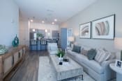Thumbnail 21 of 24 - a large living room and kitchen with wood-inspired LVP and model furnishings at Canopy Park Apartments, Alabama, 35124