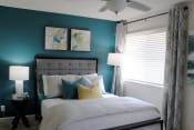Thumbnail 16 of 30 - bedroom with large window, modern ceiling fan, teal accent wall and model furnishings  at Huntsville Landing Apartments, Huntsville, Alabama