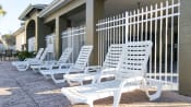 Thumbnail 11 of 15 - White pool lounge chairs on sun deck surrounded by white metal fence