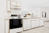 Thumbnail 11 of 25 - Virtually staged kitchen with tile floors, white appliances, and wood cabinets.