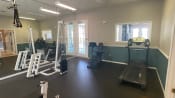 Thumbnail 13 of 31 - Fitness center with exercise bike, treadmill, elliptical, weight machines, and wall made up mirrors