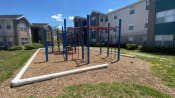 Thumbnail 4 of 31 - Red and blue playground set in a bed of mulch with building exteriors in the background