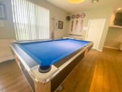 Thumbnail 13 of 30 - Blue pool table inside the leasing office on wood style flooring with tv mounted in the background