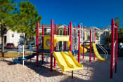 Thumbnail 3 of 17 - Colorful Playground on Sand with Building Exteriors in the Background