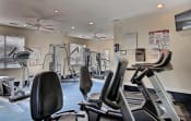 Thumbnail 4 of 5 - Fitness center with exercise equipment, two windows, wall mounted television, and two ceiling fans.
