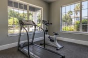 Thumbnail 16 of 24 - Fitness center with large windows featuring a treadmill and stationary bike.