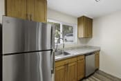 Thumbnail 16 of 18 - Kitchen with Wooden Cabinets and a Stainless Steel Refrigerator at Park 210 Apartment Homes, Edmonds, WA