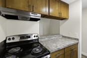 Thumbnail 9 of 18 - A Kitchen with Wood Cabinets and a Stove Top Oven at Park 210 Apartment Homes, Edmonds, WA