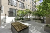Thumbnail 14 of 27 - a courtyard with a wooden bench and trees in front of  Sir Gallahad Apartment Homes, Washington, 98004