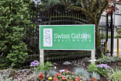 Thumbnail 7 of 30 - Swiss Gables Property Sign with Multicolor Flowers Underneath it at Swiss Gables Apartment Homes, Kent