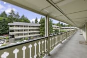 Thumbnail 3 of 30 - a balcony with a white fence and a large building in the background at Swiss Gables Apartment Homes, Kent, 98032
