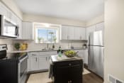 Thumbnail 5 of 31 - a kitchen with white cabinets and a black island with a bottle of wine on it