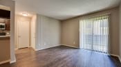Thumbnail 3 of 32 - an empty living room with a large window and wood flooring at The Manhattan Apartments, Dallas, TX, 75252
