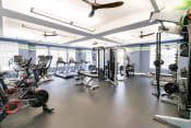 Thumbnail 10 of 22 - a gym with cardio machines and weights on the floor and a ceiling fan