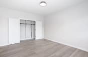 Thumbnail 23 of 23 - an empty living room with white walls and wood flooring and a white closet with