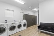 Thumbnail 24 of 28 - a laundry room with washers and dryers and a bench