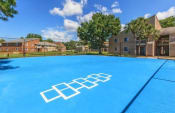 Thumbnail 29 of 35 - a large blue basketball court with apartments in the background