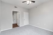 Thumbnail 8 of 28 - an empty bedroom with a ceiling fan and a door to a closet