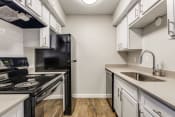 Thumbnail 1 of 19 - a kitchen with white cabinets and black appliances and a sink