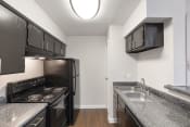 Thumbnail 12 of 37 - an empty kitchen with granite counter tops and black appliances
