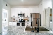 Thumbnail 6 of 42 - a white kitchen with granite counter tops and stainless steel appliances