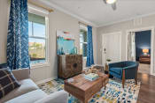 Thumbnail 6 of 25 - a living room with blue curtains and a blue chair