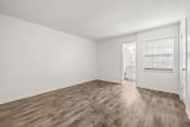 Thumbnail 8 of 29 - an empty living room with wood flooring and a door to a bathroom