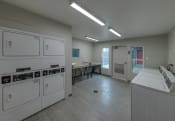 Thumbnail 15 of 19 - a laundry room in a building with washes and dryers