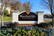 Thumbnail 1 of 22 - a sign for waterford hills apartments in front of a flower garden