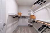 Thumbnail 9 of 30 - a walk in closet with white walls and shelves and a rack with black hangers