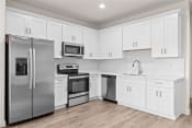 Thumbnail 2 of 24 - a white kitchen with stainless steel appliances and white cabinets