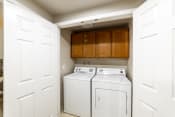 Thumbnail 11 of 28 - an empty laundry room with white appliances and wooden cabinets