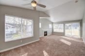 Thumbnail 14 of 38 - Apartments near JBLM - Clock Tower Village - Living Room with Fireplace, Ceiling Fan, Plush Carpet, and Expansive Windows